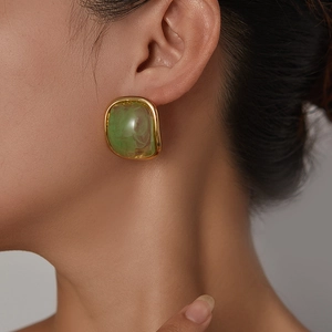 Dettaglio di orecchini vintage in resina verde con bordo dorato irregolare sulla modella