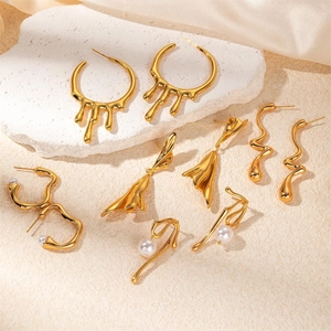 Detailed view of gold plated wing earrings with pearls on a textured stone background