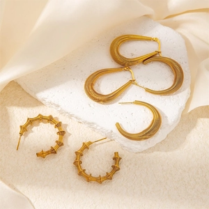 Macro shot of gold-plated ribbed hoop earrings and bamboo-style design on silk