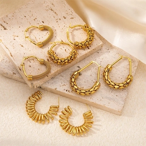 Detailed view of four assorted gold-plated titanium steel earrings on stone and silk background