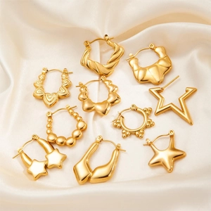 Detail of assorted gold-plated titanium earrings in heart and star shapes on silk
