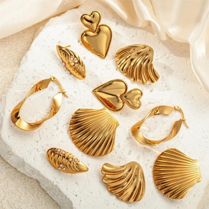 Close-up of gold-plated wing earrings with pearls on white stone and silk background