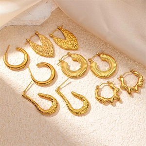 Detailed macro view of five pairs of gold-plated wing earrings on elegant stone base