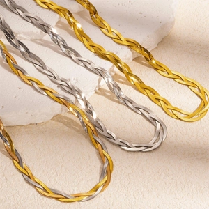 Luxe gold and silver titanium steel twist chain necklaces on a textured stone display