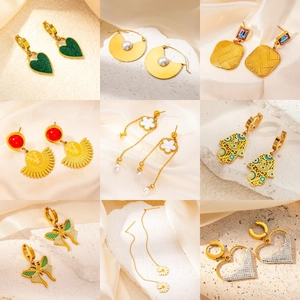 Collection of nine gold-plated wing and heart earrings on silk and stone background
