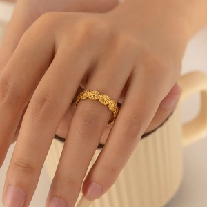 Nahaufnahme eines goldenen Gänseblümchen-Rings an einer Hand an einer Keramiktasse