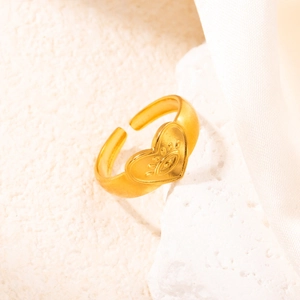 Vista macro dell'anello a cuore in oro 18k con motivo malocchio su fondo in pietra