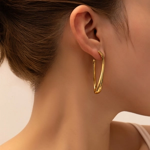 Polished 18K gold-plated twisted U-shape hoop earrings worn by a female model