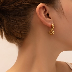 Close-up of elegant gold 18K geometric flame stud earrings on a model's ear