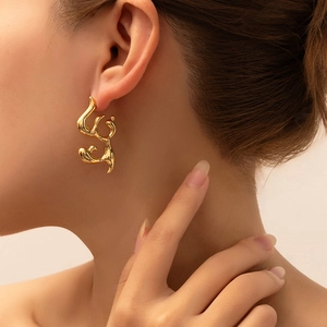 Macro detail of high-shine gold abstract liquid metal earring on female model