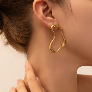 Close-up of model wearing chunky 18K gold-plated irregular wave-shaped hoop earrings