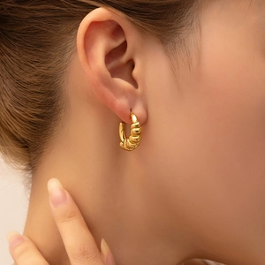 Detail view of 18K gold plated ribbed croissant C-shape hoop earrings on model