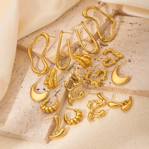 Macro shot of gold geometric earrings with lava and spiral textures on elegant silk