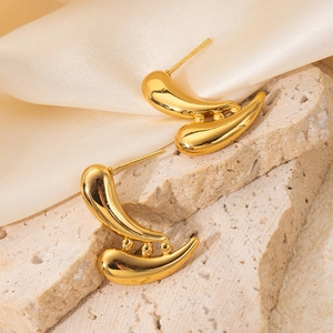 Detailed view of gold geometric drop earrings with mirror finish on stone and silk background