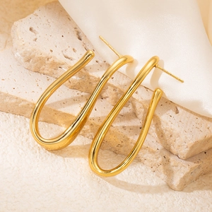 Close-up of elegant 18K gold-plated U-shaped earrings on textured stone and silk