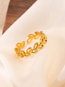 Detail of adjustable hollow leaf gold ring placed on elegant silk fabric