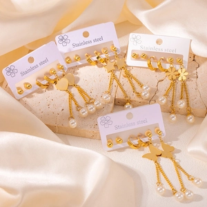Détails de parures de boucles d'oreilles en acier doré avec perles et cœurs sur socle
