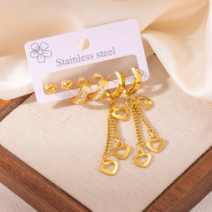 Détail d'un ensemble de boucles d'oreilles en acier doré avec cœurs et cristaux