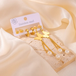Détail d'un ensemble de boucles d'oreilles en acier doré avec perles et glands papillon