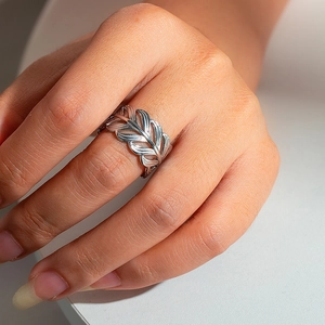 Detail shot of a silver hollow feather ring in stainless steel with premium metallic texture