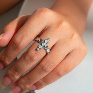 Macro view of a silver cross ring with hematite stones worn on a finger
