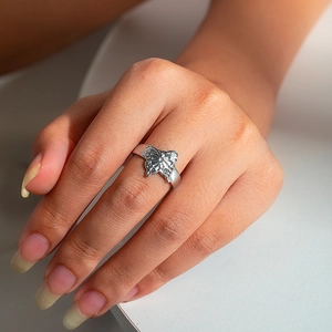 Close-up of a silver butterfly ring with textured wings on a finger for size reference
