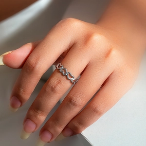 Macro shot of silver hollow heart-shaped ring band worn on finger with minimalist detail