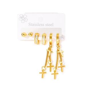 Détail de trois paires de boucles d'oreilles en acier doré avec croix et anneaux