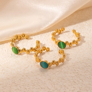 Detailed macro of vintage 18K gold-plated rings with green cat-eye stones and wavy texture