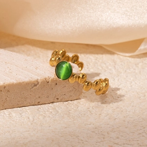 Detail of 18K gold-plated vintage ring with green gemstone on smooth fabric background