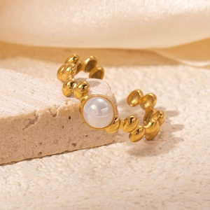 Close-up of vintage 18K gold plated steel ring with white pearl on rock texture