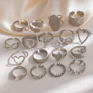 Macro shot of 16-piece silver heart and infinity rings set on elegant silk fabric