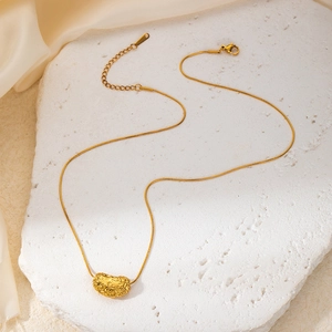 Close-up of a gold-plated snake chain necklace with a textured heart-shaped relief pendant