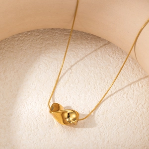 Macro shot of gold snake chain with polished irregular distorted heart pendant