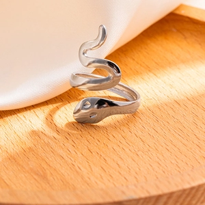 Dettaglio macro di un anello a serpente in acciaio inossidabile argento lucido su legno
