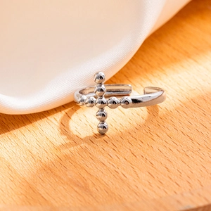 Dettaglio macro dell'anello a croce d'argento con grani su fondo in legno caldo