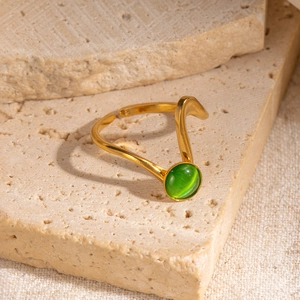 Dettaglio dell'anello ondulato in oro con pietra occhio di gatto verde su base di pietra