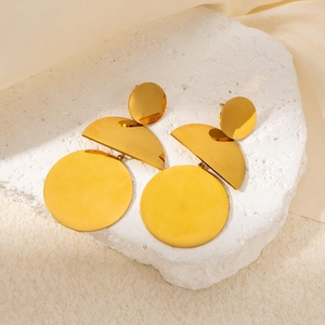 Dettaglio di orecchini geometrici in oro 18k su superficie di marmo bianco liscio