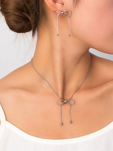 Dettaglio del set di gioielli con fiocco argento e pendenti a nappa su una modella