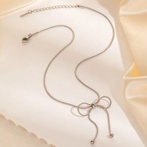 Dettaglio della collana in acciaio con ciondolo a fiocco e nappe di perline su seta
