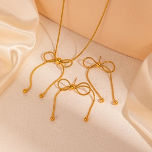 Dettaglio del set di gioielli dorati con fiocchi, collana con nappe ed eleganti orecchini