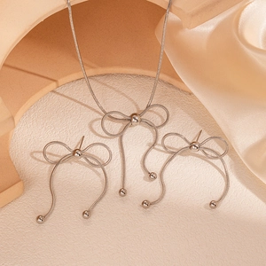 Dettaglio del set di gioielli con fiocco argento e nappe su seta champagne