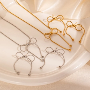 Dettaglio di un set gioielli a fiocco con collana e orecchini su sfondo di seta elegante