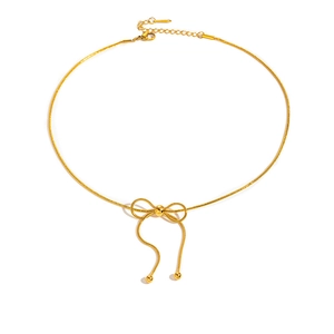 Dettaglio della collana con fiocco dorato, perla centrale e maglia a serpente