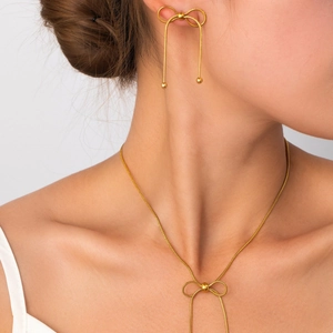 Elegante set di gioielli dorati con fiocco, collana con nappe e orecchini indossati