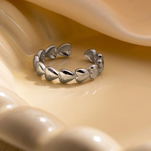 Détail de la bague ouverte en acier titane argenté avec motifs de cœurs gravés