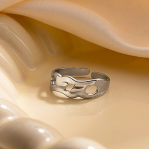 Détail de la bague en acier argenté avec bordure ondulée irrégulière et motif évidé