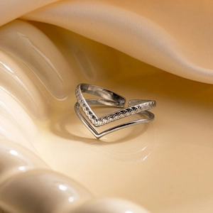 Détail d'une bague double en V argentée gravée posée sur un tissu en soie élégant
