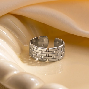 Gros plan d'une bague en titane argentée avec des textures géométriques de briques modernes