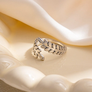 Dettaglio dell'anello regolabile in argento vintage con foglie e trame su un vassoio di ceramica